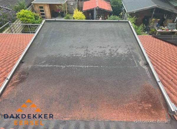 Verouderd plat dak met slijtage tussen schuine daken in Eersel Verouderd plat dak met slijtage tussen schuine daken in Eersel